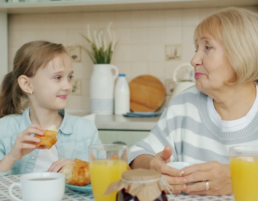Grandmother and granddaughter sharing breakfast at a sunlit table