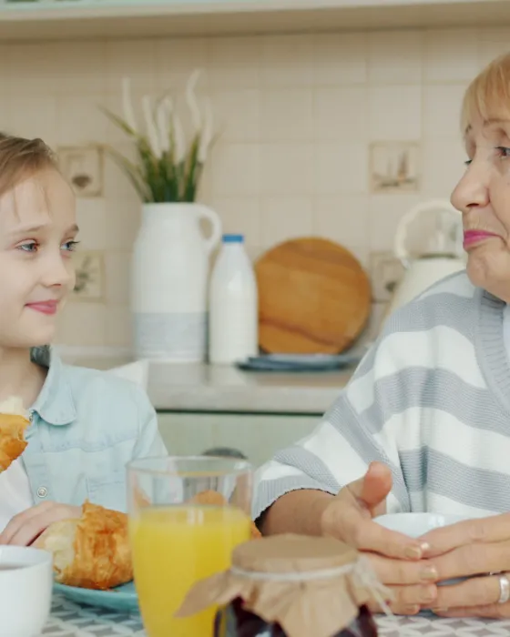 Grandmother and granddaughter sharing breakfast at a sunlit table