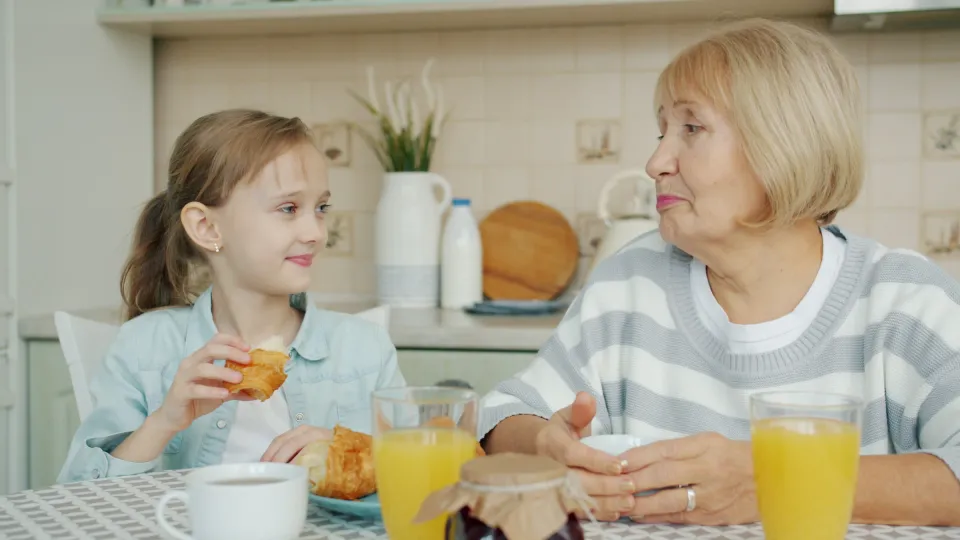 Grandmother and granddaughter sharing breakfast at a sunlit table