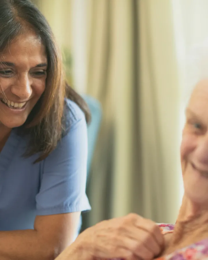 Smiling nurse caring for an elderly patient in a sunlit room